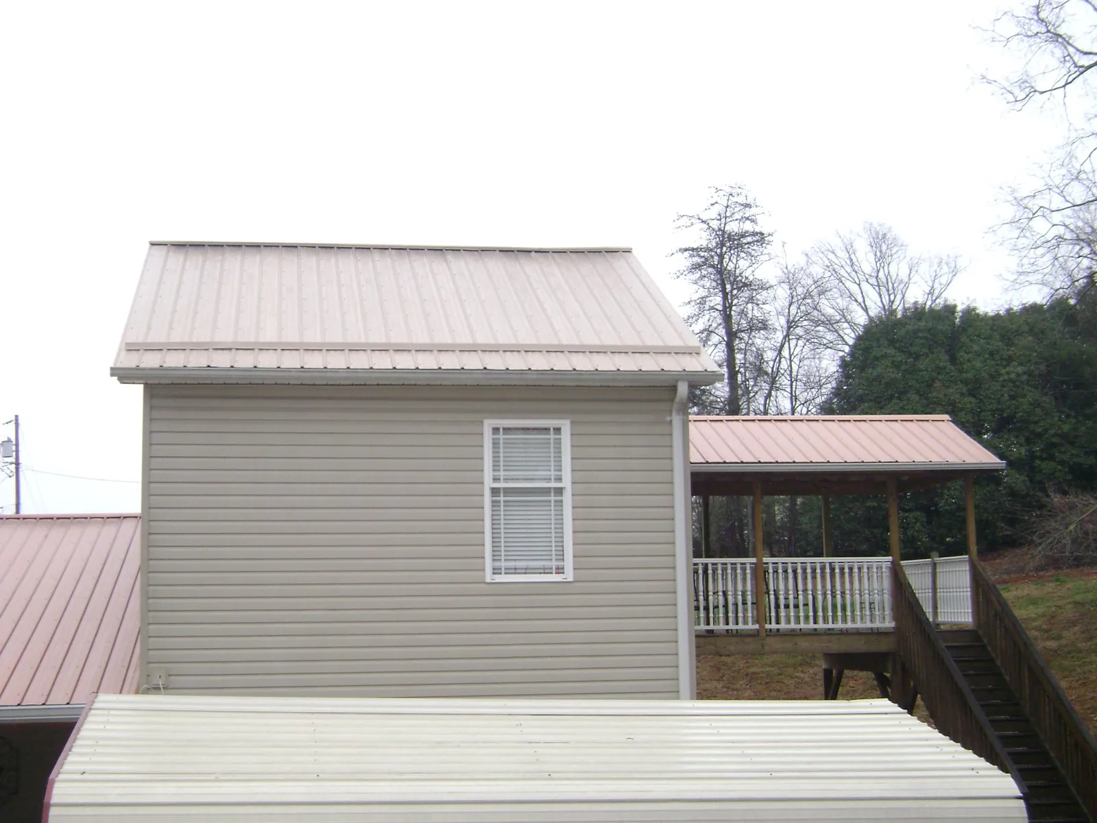 Tan metal roofs on a two story addition and attached porch, from a Roof Replacement job in Wildersville