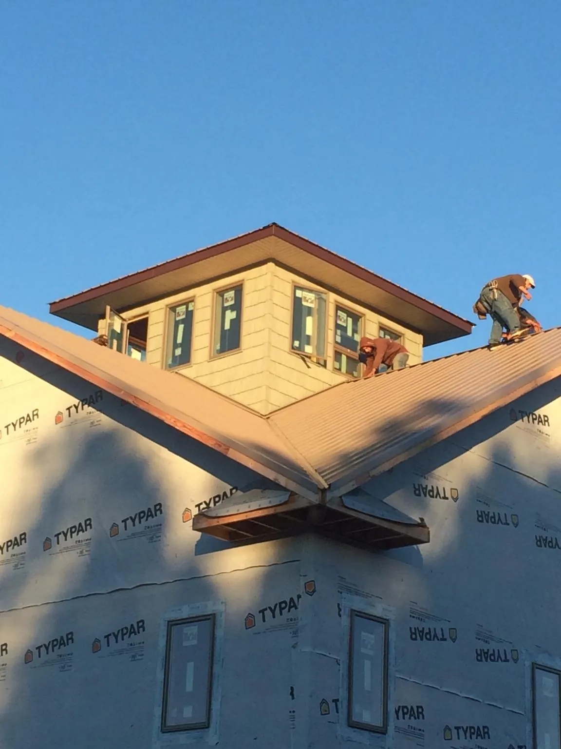 Roofers working around a rooftop cupola on a new metal roof at sunset — Roof Waterproofing in Wildersville by Roofing Brothers